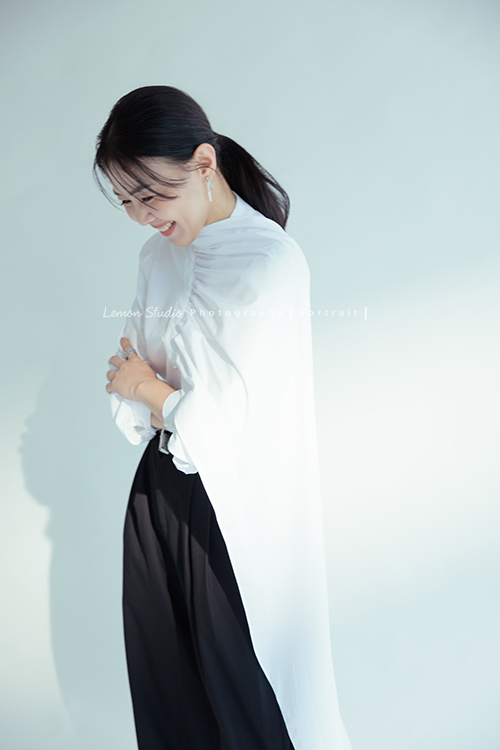 形象顧問Ivy的形象照，很喜歡她在鏡頭前的肢體語言，對整體形象＆服裝的搭配有很多想法的她，目前也和我們合作，這張是Ivy穿上白色很有特色的上衣、站著雙手在身體前方交疊、低頭笑著的一瞬間、是一張很美的形象顧問形象照！