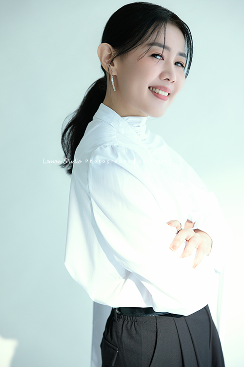 形象顧問Ivy的形象照，很喜歡她在鏡頭前的肢體語言，對整體形象＆服裝的搭配有很多想法的她，目前也和我們合作，這張是Ivy穿上白色很有特色的上衣、站著雙手在身體前方交疊、身體側站並轉過頭來看著鏡頭微笑、是一張很美的形象顧問形象照！