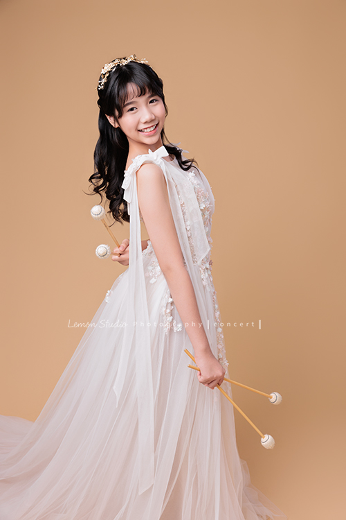 音樂班的 Lily畢業前來拍音樂班畢業音樂寫真照，Lily的活潑與大方在鏡頭前自然流露，這張是Lily穿著一襲白色的禮服、拿著馬林巴木琴槌擺在身體旁邊及後面看著鏡頭笑得很甜美的一張音樂班畢業音樂寫真照！