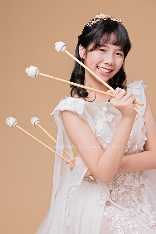 音樂班的 Lily畢業前來拍音樂班畢業音樂寫真照，Lily的活潑與大方在鏡頭前自然流露，這張是Lily穿著一襲白色的禮服、拿著馬林巴木琴槌看著鏡頭笑得很甜美的一張音樂班畢業音樂寫真照！