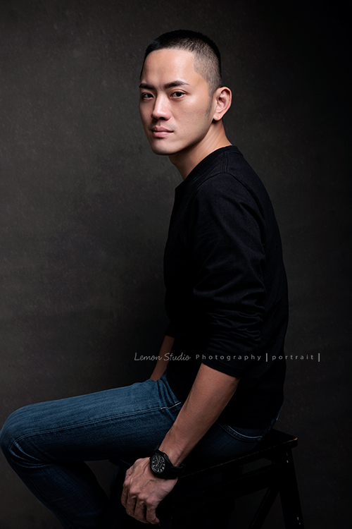 品牌創辦人 Mike來拍形象照，低調、沉穩，帶著一點故事感，也隱約帶著哲學及神秘感的形象照，這張是Mike坐在椅子上、側身兩手放在身旁、轉頭很酷地看著鏡頭的形象照！是一張低調很有質感的形象照！