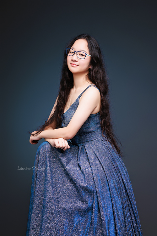 就讀高中音樂班主修鋼琴的Diana，來拍屬於她的音樂寫真，黎爸拍下兩種截然不同感覺的Diana，這張是Diana穿著一襲藍色的禮服、戴上眼鏡，坐在椅子上、雙手交疊在前方的腿上，坐姿很端正優雅、並沈穩有自信地看著鏡頭，是一張很美的音樂寫真照！