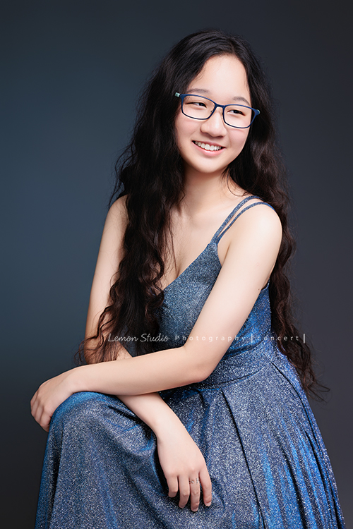 就讀高中音樂班主修鋼琴的Diana，來拍屬於她的音樂寫真，黎爸拍下兩種截然不同感覺的Diana，這張是Diana穿著一襲藍色的禮服、戴上眼鏡，坐在椅子上、雙手交疊在前方的腿上，坐姿很端正優雅、看著側邊甜美地微笑著沒有看鏡頭，是一張很美的音樂寫真照！