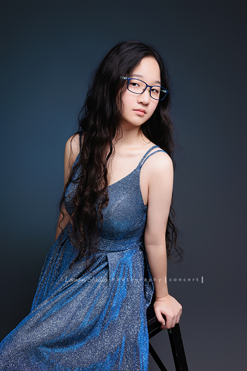 就讀高中音樂班主修鋼琴的Diana，來拍屬於她的音樂寫真，黎爸拍下兩種截然不同感覺的Diana，這張是Diana穿著一襲藍色的禮服、戴上眼鏡，坐在椅子上、雙手放在椅子後方，很優雅地側坐在椅子上、並沈穩酷酷地看著鏡頭，是一張很美的音樂寫真照！
