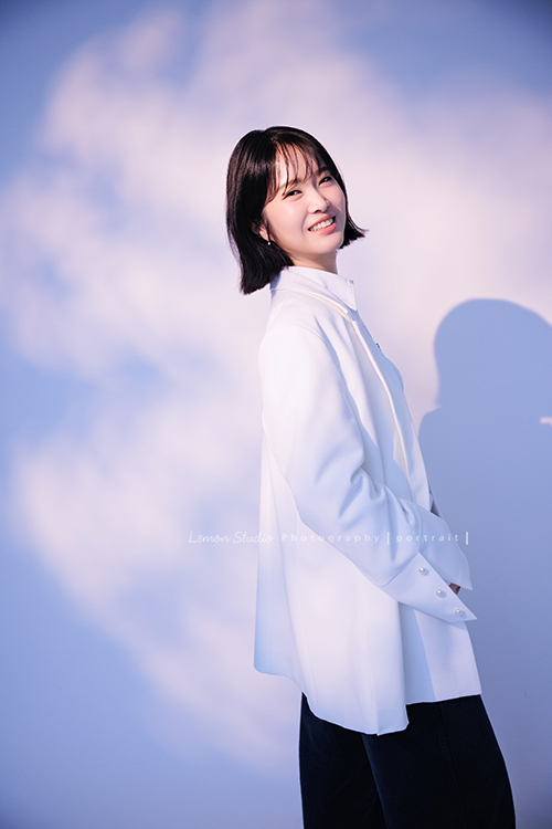 講師Tiffany來拍照，這次我們一起整理出帶點日韓系的風格，有些細微的表情與狀態，很耐看，這張是Tiffany身穿白色外套，雙手放在身體前方、側身轉過頭來看著鏡頭微笑，很自然的一張形象照！