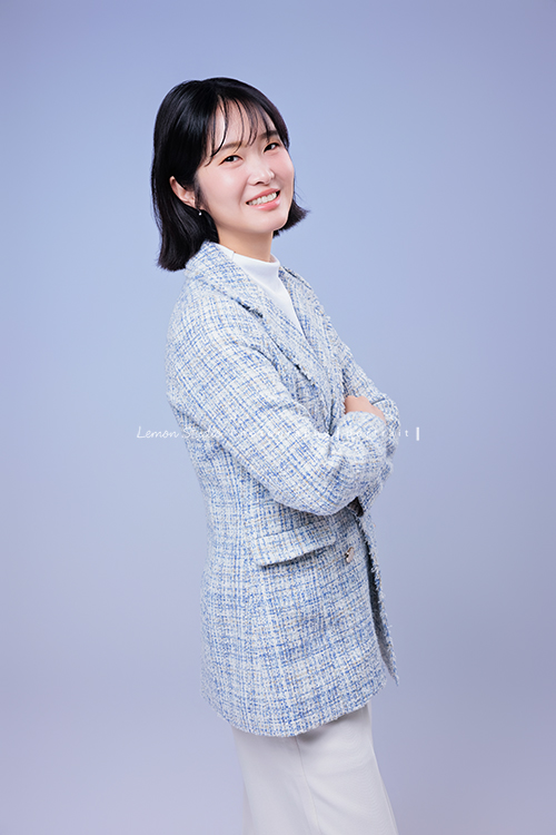 講師Tiffany來拍照，這次我們一起整理出帶點日韓系的風格，有些細微的表情與狀態，很耐看，這張是Tiffany身穿淺藍色系外套，雙手放在身體前方、側身轉過頭來看著鏡頭微笑的形象照！