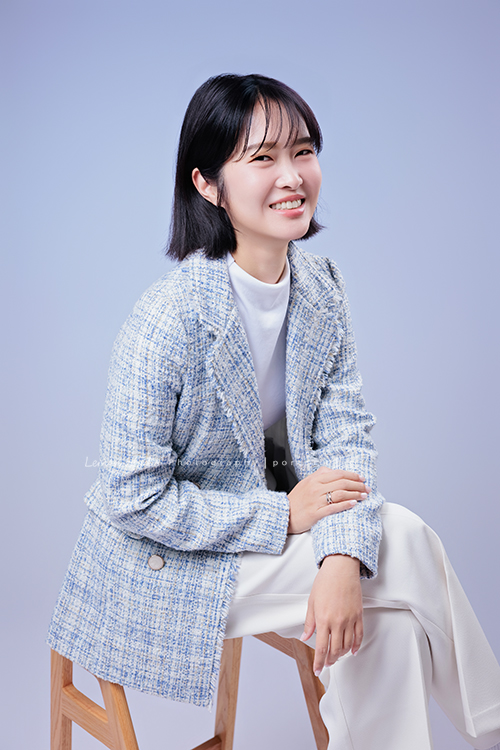 講師Tiffany來拍照，這次我們一起整理出帶點日韓系的風格，有些細微的表情與狀態，很耐看，這張是Tiffany身穿淺藍色系外套坐在椅子上，雙手放在身體前方、看著鏡頭微笑的形象照！