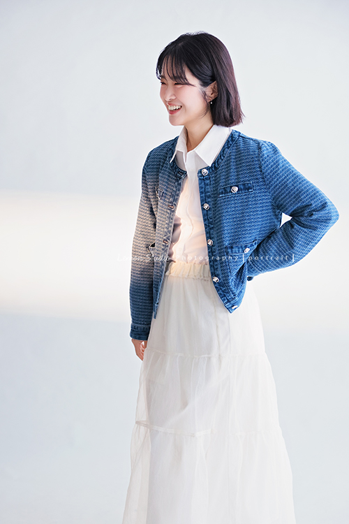 講師Tiffany來拍照，這次我們一起整理出帶點日韓系的風格，有些細微的表情與狀態，很耐看，這張是Tiffany身穿藍色短版外套及白色長裙，一手叉腰、沒有看鏡頭微笑的一張很自然的形象照！
