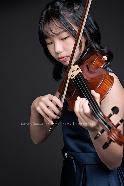 岑即將從國小弦樂團畢業,這一天,我們拍下了許多不同樣子的岑,把這些輕輕停留的瞬間,就讓相片替她好好留住,這張是岑身穿藍色小禮服、手拿著提琴及弓、正專注地在拉提琴沒有看鏡頭的一張音樂寫真照!