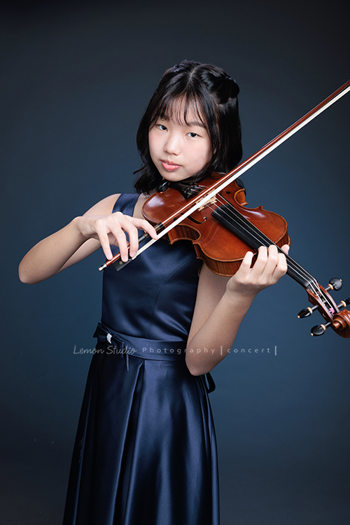 岑即將從國小弦樂團畢業,這一天,我們拍下了許多不同樣子的岑,把這些輕輕停留的瞬間,就讓相片替她好好留住,這張是岑身穿藍色小禮服、手拿著提琴及弓、沈穩地看著鏡頭的音樂寫真照!