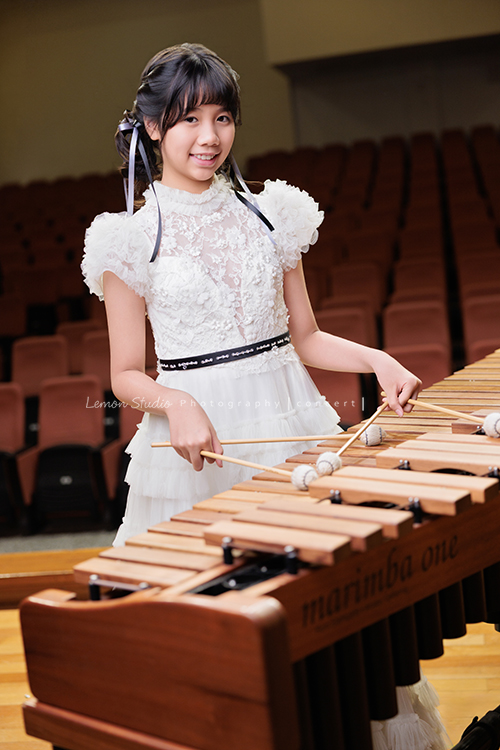 音樂班的 Lily畢業前來拍音樂班畢業音樂寫真照，Lily的活潑與大方在鏡頭前自然流露，這張是Lily穿著一襲可愛的白色禮服、正在敲打馬林巴木琴、看著鏡頭笑得很甜美的一張音樂班畢業音樂寫真照！