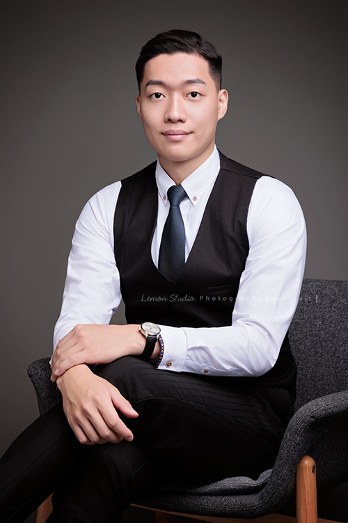 圓璽不動產專業服務顧問Michael來拍形象照,高大俊挺的Michael拍出專業感的形象照,這張是Michael穿著白色襯衫及背心、坐在椅上,兩手很自然地放在腿上,自信且微笑地看著鏡頭的一張很帥氣的房仲形象照!
