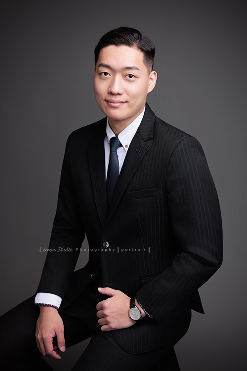圓璽不動產專業服務顧問Michael來拍形象照,高大俊挺的Michael拍出專業感的形象照,這張是Michael穿著西裝外套坐在椅上,兩手很自然地放在腿上,自信且微笑地看著鏡頭的一張很帥氣的房仲形象照!