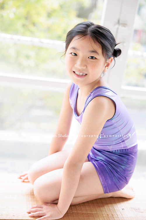 Vivien媽麻一家幾乎每年都會來拍照,三個孩子都在自己喜歡的領域裡成長著,這次小妹 Tiana帶著體操服來拍照,這張是Tiana蹲坐在木椅上、轉頭看向鏡頭微笑著的模樣,是一張很可愛的體操運動寫真!