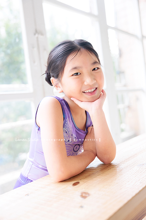Vivien媽麻一家幾乎每年都會來拍照,三個孩子都在自己喜歡的領域裡成長著,這次小妹 Tiana帶著體操服來拍照,這張是Tiana穿著體操服一手托著下巴兩側、另一手搭在托著下巴的手的手臂上,笑容很甜美地看著鏡頭,是一張很可愛的體操運動寫真!