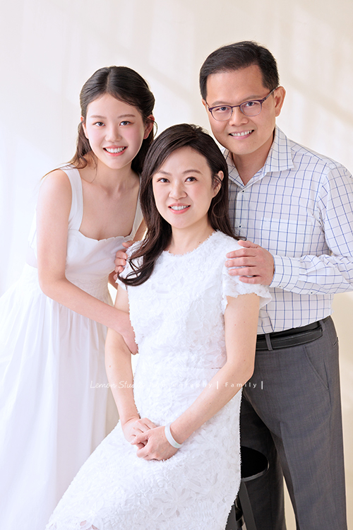 Irene媽麻一家暑假回台灣時來拍攝家庭照，今天先來分享一家三口的家庭照，Irene媽麻特別準備了白色系洋裝，一家三口在 Amber 即將踏入大學前，留下這段屬於一家人的珍貴時光，這張是Irene媽麻一家的全家福，Irene媽麻坐在中間，爸拔和Amber站在她的兩旁，兩人的手都搭在Irene媽麻身上！一家人微笑著看著鏡頭！是一張很美很自然的全家福寫真！