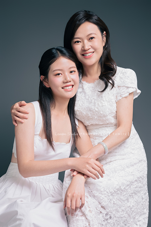 Irene媽麻一家暑假回台灣時來拍攝家庭照，今天先來分享一家三口的家庭照，Irene媽麻特別準備了白色系洋裝，一家三口在 Amber 即將踏入大學前，留下這段屬於一家人的珍貴時光，這張是Irene媽麻和女兒Amber的合照，兩人坐著，Amber靠向媽麻，兩人微笑著看著鏡頭，是一張很美的母女寫真！